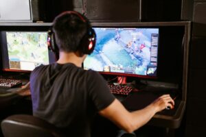 Young teen male playing PC combat video game with headphones on