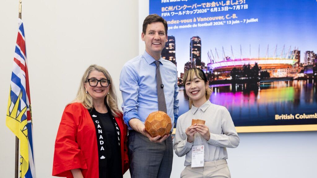 Agriculture Minister Lana Popham and Premier David Eby holding wood leather soccer ball